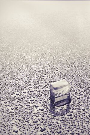 Piece of ice in water droplets on glassの写真素材