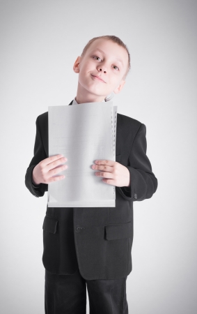 Boy in a black suit presses the stack of paperの写真素材