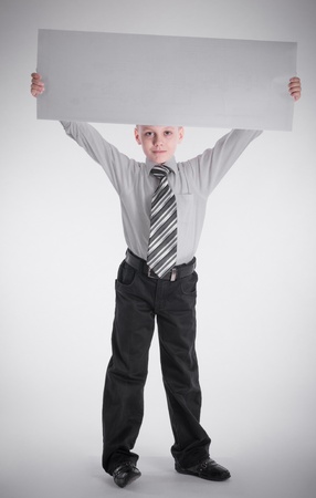 A boy holding nameplate over his headの写真素材