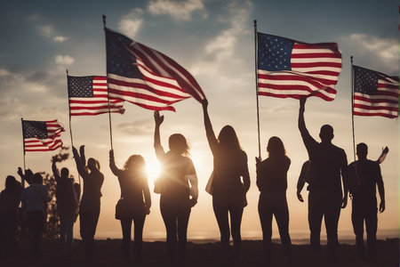 Silhouette of a group of young people holding American flags during sunsetの写真素材