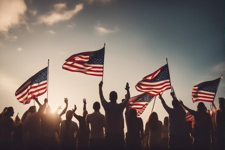 Silhouettes of people waving the American flag on a sunny dayの写真素材