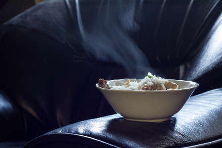 bowl of a hot boiled-rice on a black chairの写真素材
