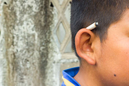 cigarette on a boy earの写真素材