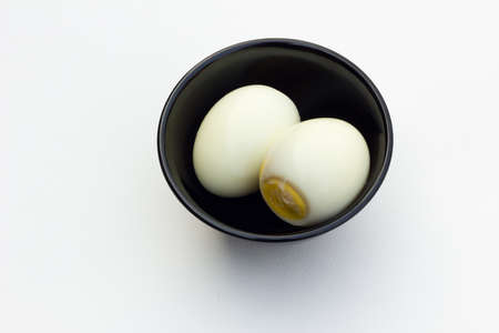 two boiled eggs in black bowl in white backgroundの写真素材