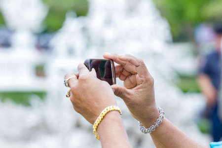 rich woman hands taking a picture at a temple in Thailandの写真素材