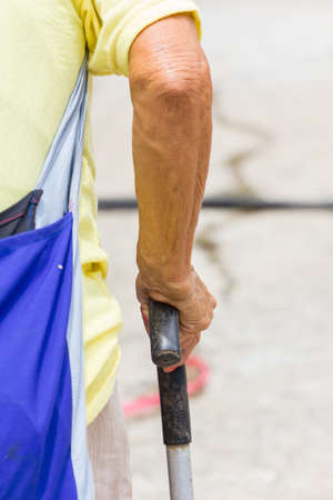 Old woman hand leans on walking stick, close-upの写真素材