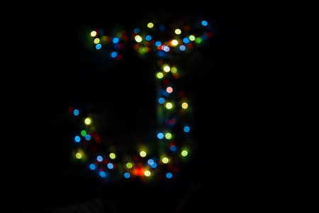 colorful letter J made of blurred circular bokeh on black backgroundの写真素材