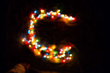 colorful letter C made of blurred circular bokeh on black backgroundの写真素材