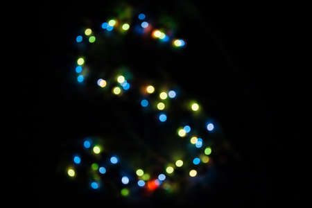 colorful letter S made of blurred circular bokeh on black background