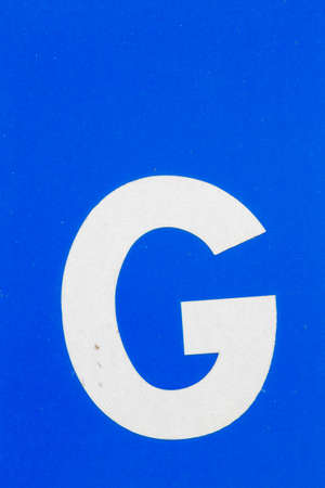 Closeup white letter G from traffic road sign in thailand on blue の写真素材