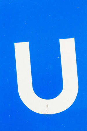 closeup white letter U from traffic road sign in thailand on blue background