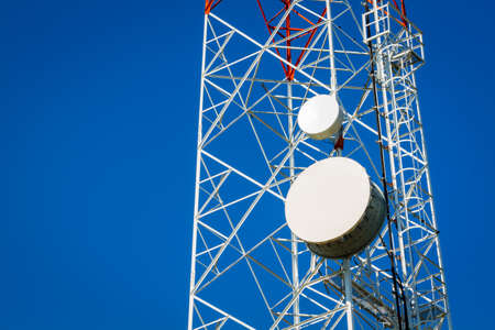 Close-up of a telecommunications tower with blue clear sky.