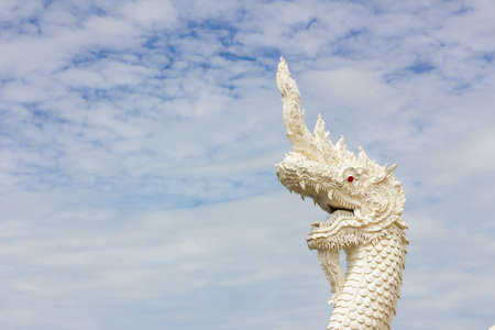 serpent king or king of naga statue in thai temple in background of cloudy sky.の写真素材
