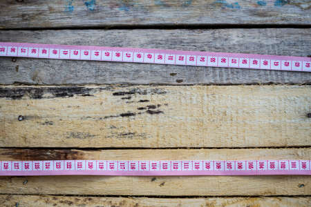 two tape measures in horizontal line on old wooden background. Top view. copyspace in the middle.の写真素材