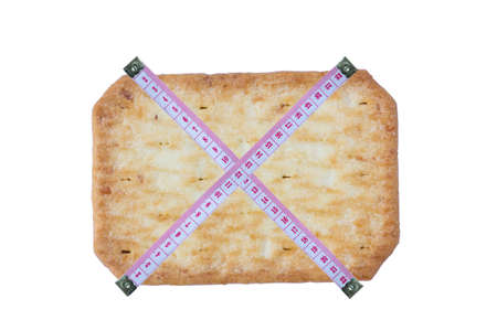 cross measuring tape with saltine soda cracker isolated on white background, diet concept.の写真素材