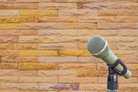 microphone on a stand with blurred wall made from yellow sandstone bricks, copyspaceの写真素材
