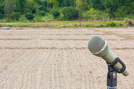 microphone on a stand with blurredbackground of plowed field with tractor traces, copyspaceの写真素材