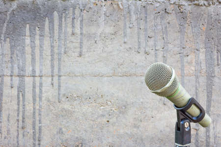 microphone on a stand with blurred concrete wall with cement drips and copyspace in the middleの写真素材