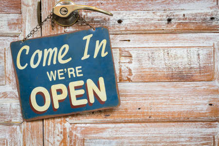 Come In We're Open on the wooden door, copyspace on the right.