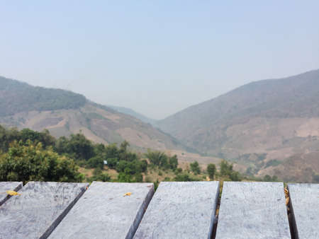 wooden table perspective with blurred deforested mountain and sky backgroundの写真素材