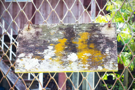 Old wood with moss and fungus hanging on wire fenceの写真素材
