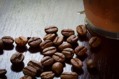 extreme closeup coffee beans with Iced coffee in plastic glass, dark tone