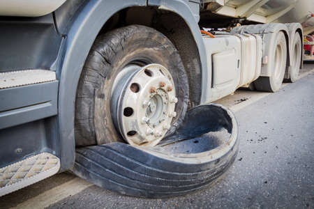 closeup damaged 18 wheeler truck burst tires by highway streetの写真素材