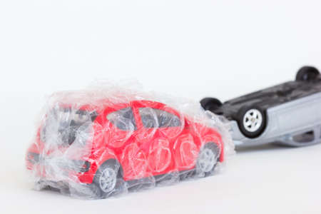 horizontal photo of two cars toy in accident scene. The safe red one is protected with air bubble on blank background.の写真素材