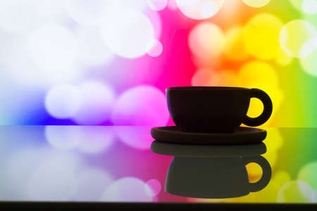 horizontal photo of silhouette coffee cup on colorful bokeh background.の写真素材