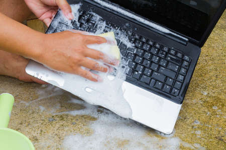 closeup cleaning computer notebook with dish washing soap, technology conceptの写真素材