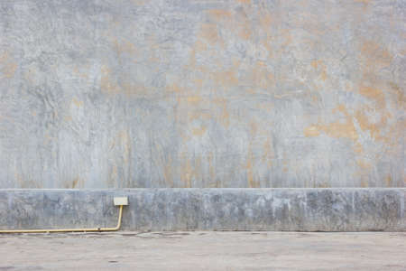 grungy mud dirty concrete wall background with yellow PVC pipe on the ground.の写真素材