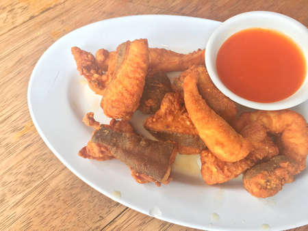 Horizontal photo of closeup fried fish with chili sauce on wooden table. Shallow depth of field.の写真素材