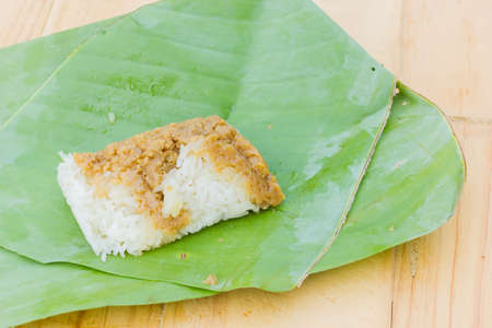 sticky rice and creamy  egg custard wrapped with banana leaf on wooden background, Thai dessert.の写真素材
