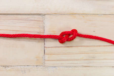 Figure-eight knot made with red rope on wooden background.の写真素材