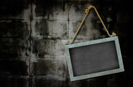 iron blackboard hanging on old grunge wall texture with vignette.の写真素材