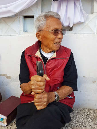 CHIANG RAI, THAILAND - FEBRUARY 5 : unidentified smiling old asian male with a watch holding a cane on February 5, 2017 in Chiang rai, Thailand.のeditorial素材