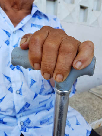 closeup hand of old asian male with a watch holding a caneの写真素材