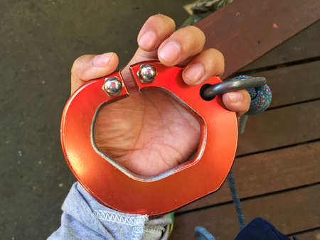 horizontal photo of big red carabiner on man's left hand