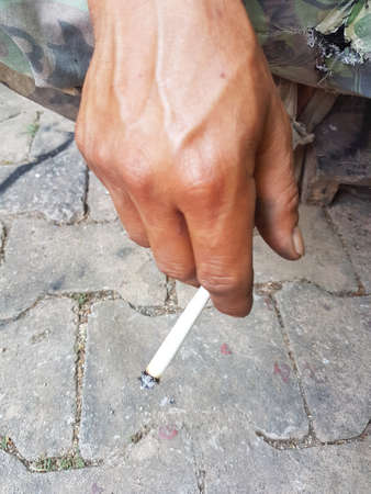 closeup asian man's hand holding burning traditional cigarette in handの写真素材