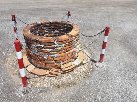 old well on the road with chain and red white sign aroundの写真素材