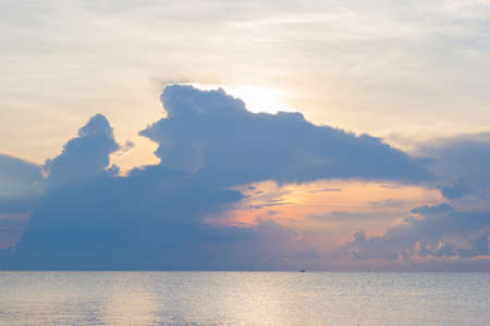 sunset over the sea and silhouette small fishing boat with storm comingの写真素材