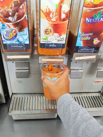 CHIANG RAI, THAILAND - MAY 8 : close-up asian man holding plastic glass filling iced tea with milk in 7-Eleven on May 8, 2017 in Chiang rai, Thailand.のeditorial素材