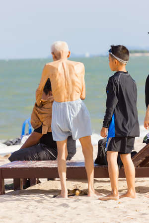 PHETCHABURI, THAILAND - APRIL 7 : unidentified asian old man standing on the beach with his family on April 7, 2017 in Phetchaburi, Thailand.のeditorial素材