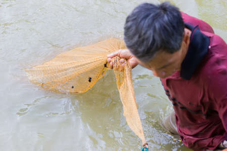 CHIANG RAI, THAILAND - MAY 21 : unidentified fisherman in dark red polo shirt pulling the net out of the pond on May 21, 2017 in Chiang rai, Thailand.のeditorial素材