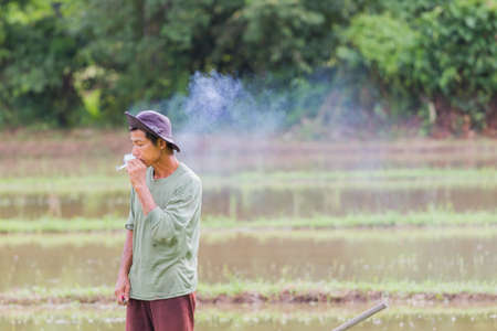 CHIANG RAI, THAILAND - JUNE 16 : Unidentified asian male farmer smoking during working in the field on June 16, 2017 in Chiang rai, Thailand. Horizontal photo with copyspaceのeditorial素材