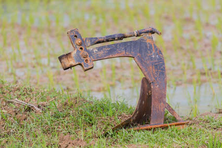 rusty plough handle iron on the rice field