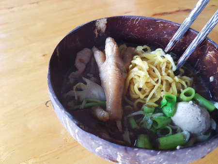 close-up noodles with chicken legs in coconut shell bowl, copyspace on the leftの写真素材