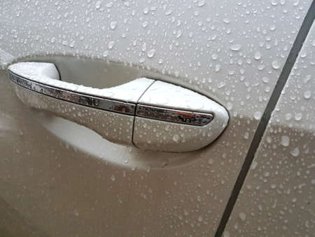 front door handle of a white car in the rain.の写真素材