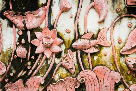 Fish and lotus stone carving with moss on temple wall
