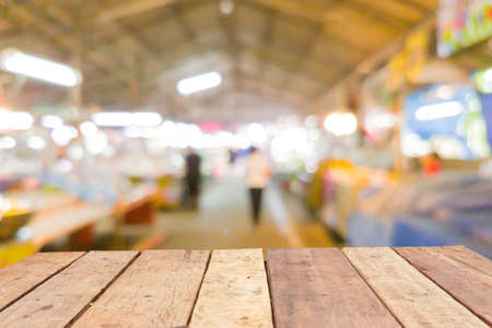 Wooden board empty table in front of blurred Thai fresh-food market background with bokehの写真素材